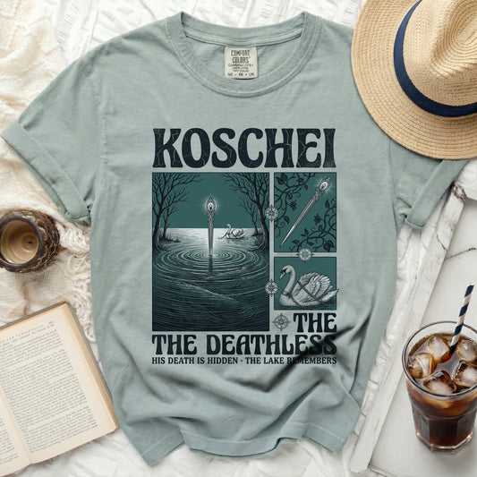 Green t-shirt with "Koschei The Deathless" graphic, swans, and lake scene.