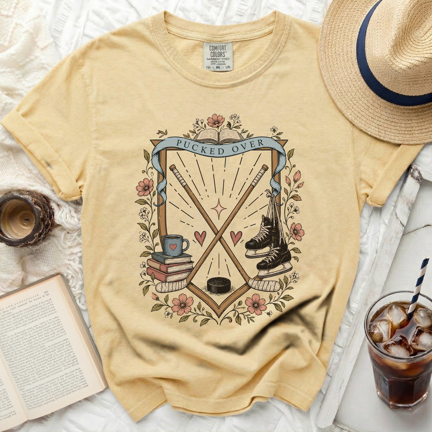 Yellow t-shirt with hockey sticks, skates, books, and "Pucked Over" text.