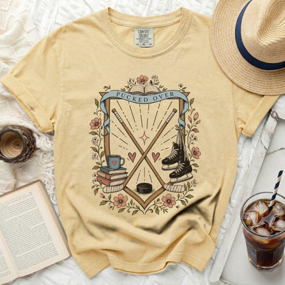 Yellow t-shirt with hockey sticks, skates, books, and "Pucked Over" text.