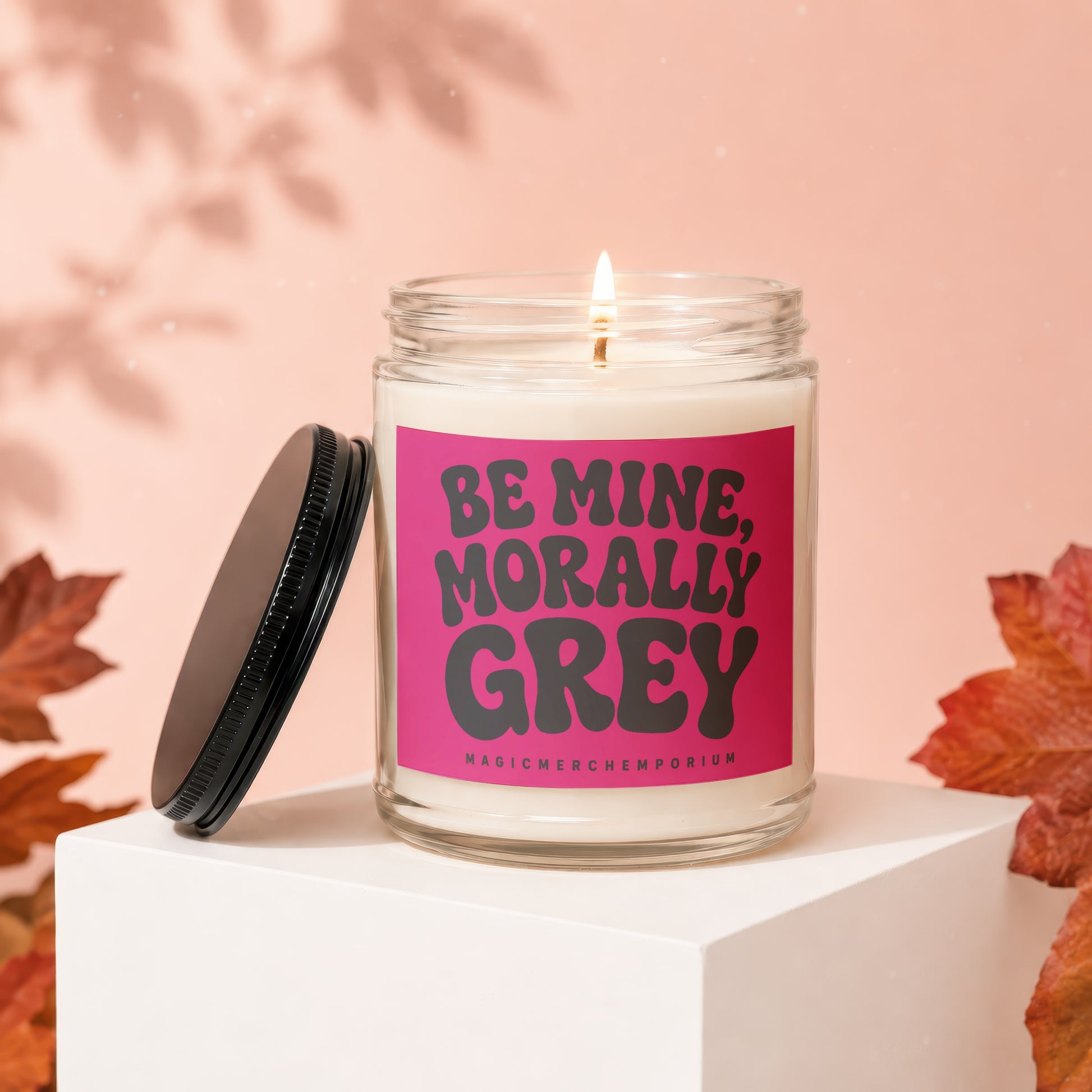Glass candle with pink label reading "Be Mine, Morally Grey"