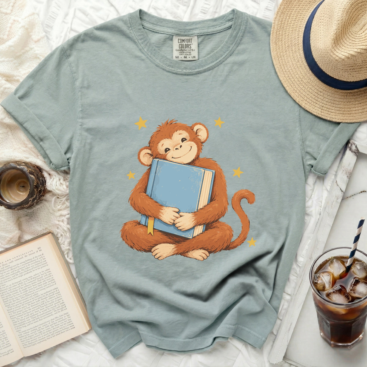 Cartoon monkey hugging a blue book with yellow stars on a t-shirt.