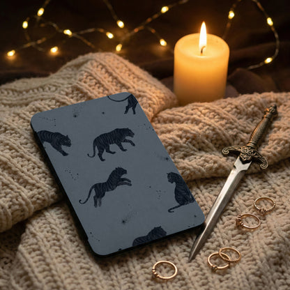 Dark patterned phone case with tigers and constellations on a textured knit blanket.