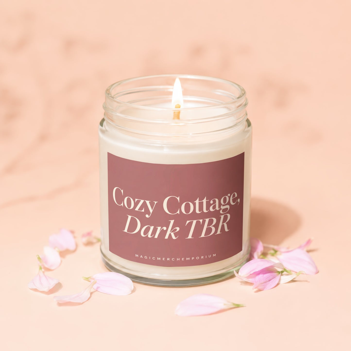 Lit candle with "Cozy Cottage, Dark TBR" label surrounded by pink petals.
