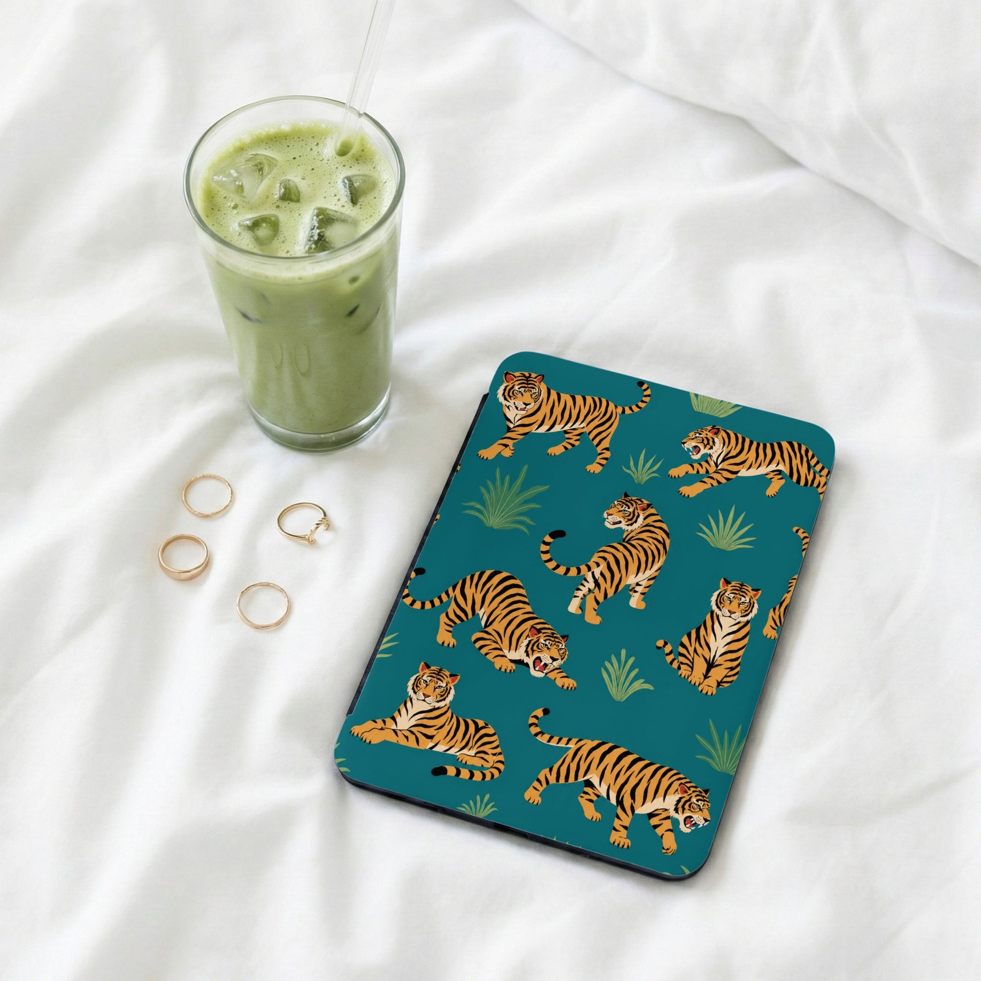Teal protective case with a repeating tiger pattern and ice matcha latte.