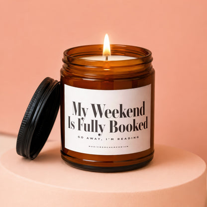 Amber jar candle with lit flame and label reading "My Weekend Is Fully Booked."