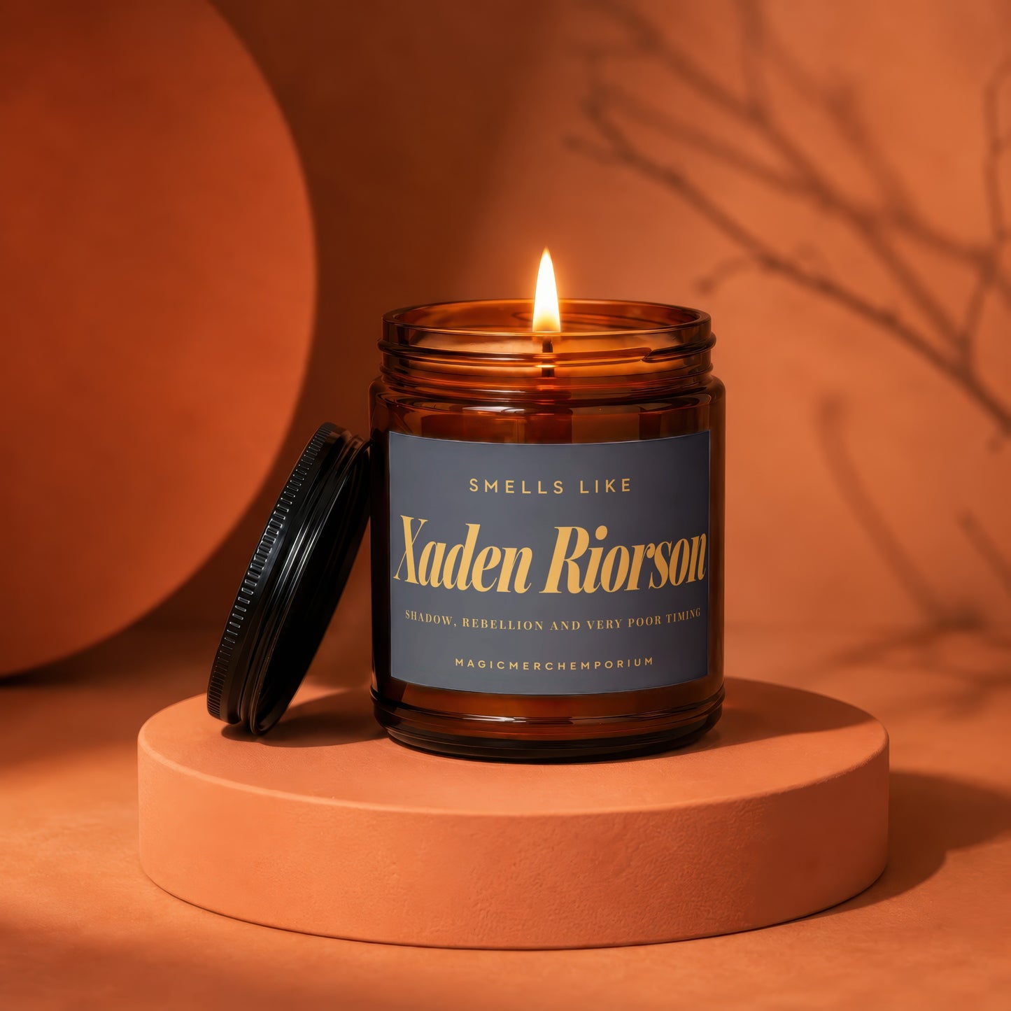 Lit candle in amber jar labeled "Xaden Riorson" on an orange pedestal.