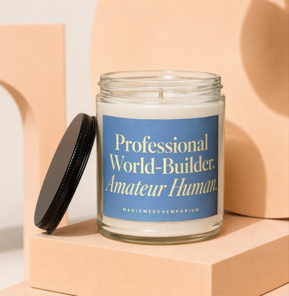 Glass candle with blue label reading "Professional World-Builder. Amateur Human."