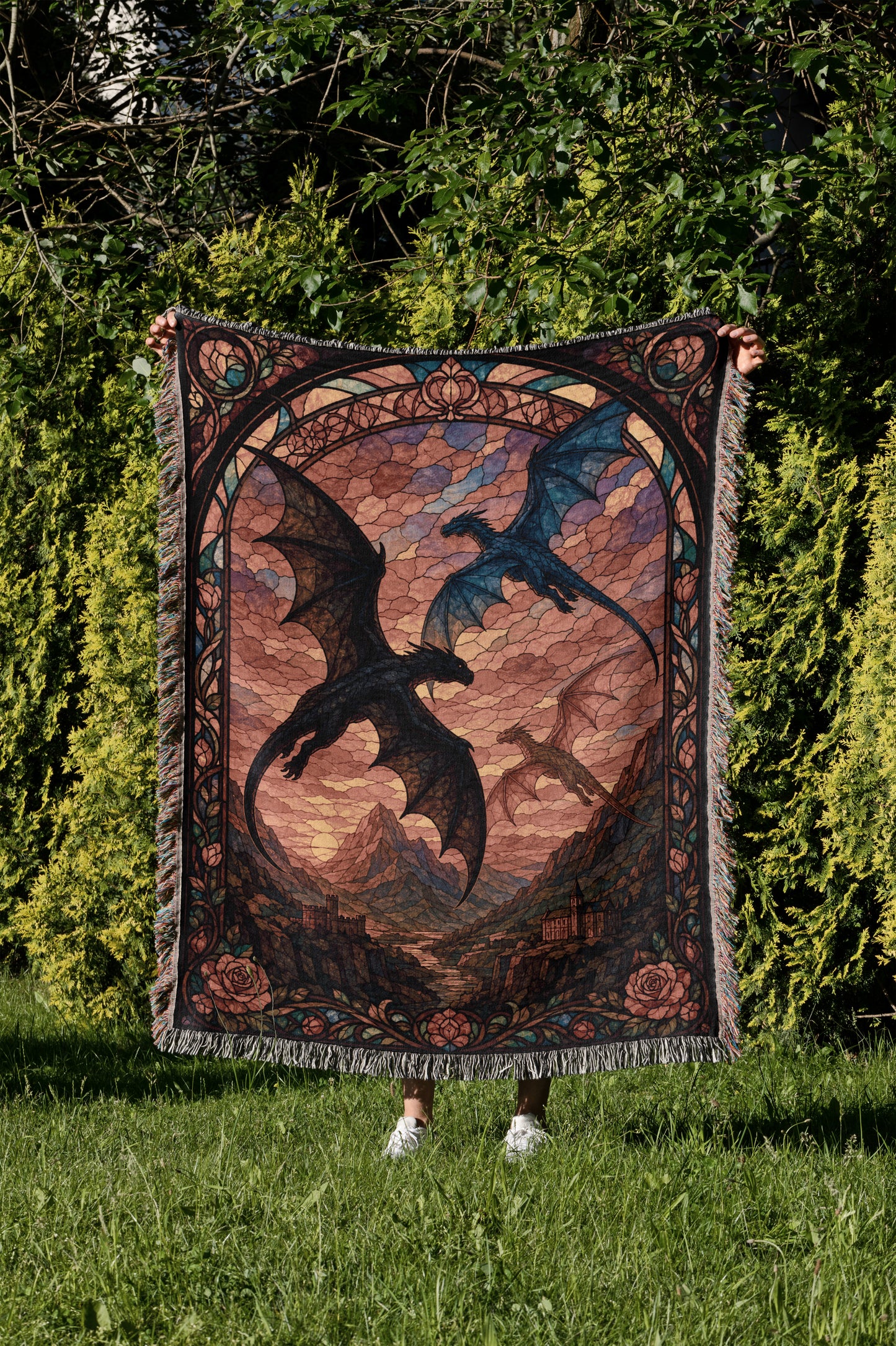 A person is holding up a large, colorful tapestry featuring a dragon design against a backdrop of a sunset sky.