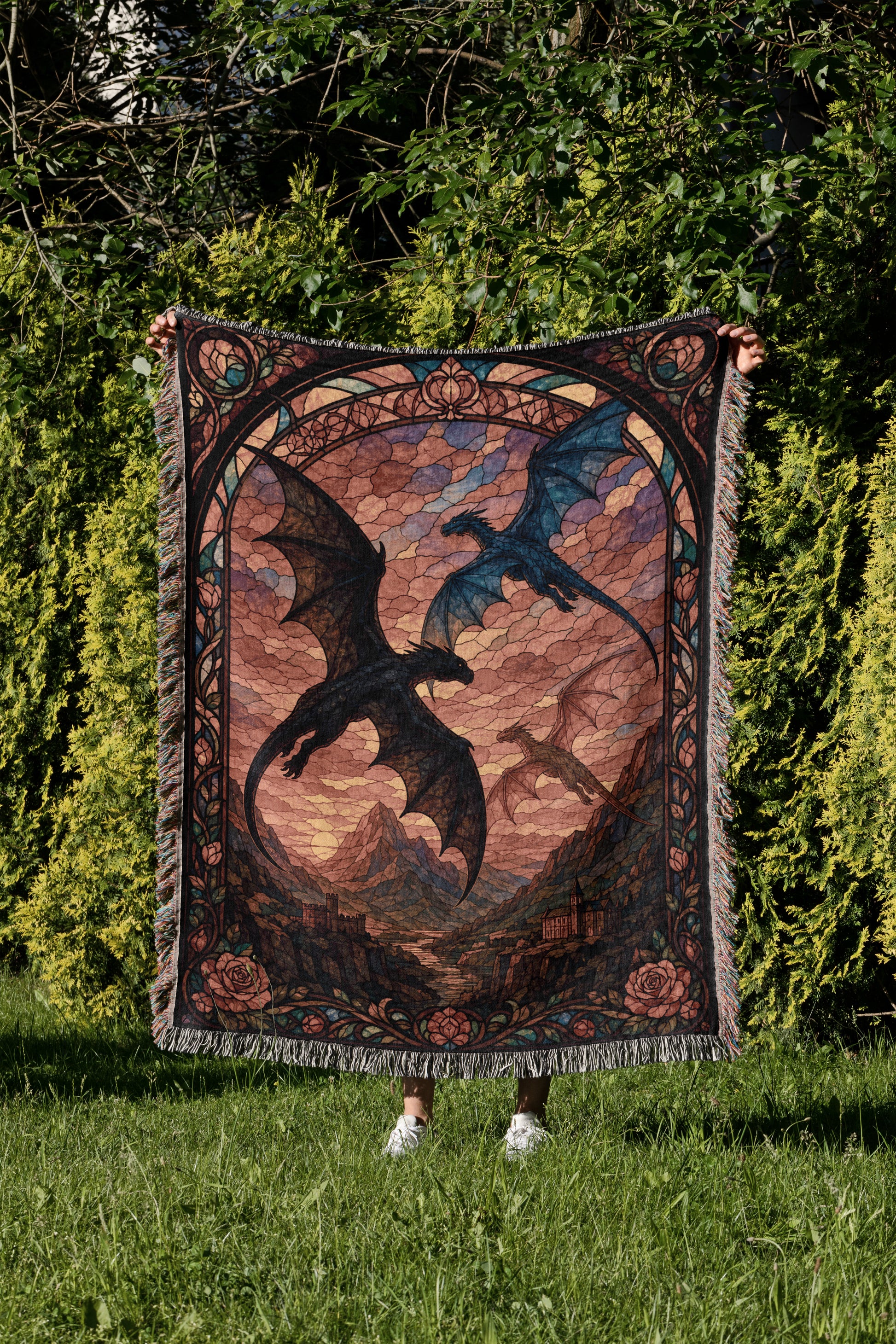 A person is holding up a large, colorful tapestry featuring a dragon design against a backdrop of a sunset sky.