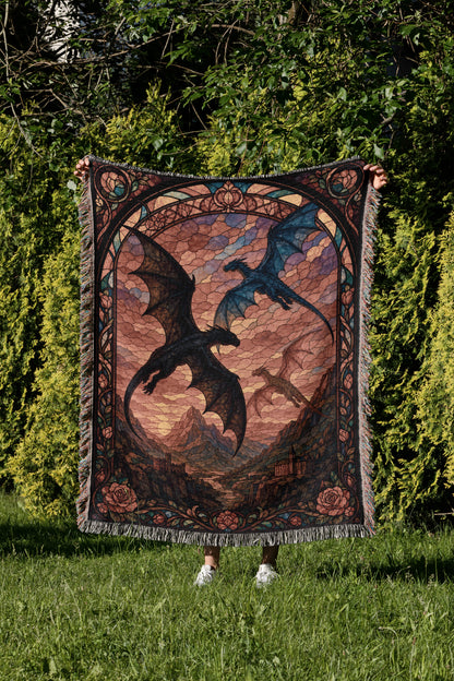 A person is holding up a large, colorful tapestry featuring a dragon design against a backdrop of a sunset sky.