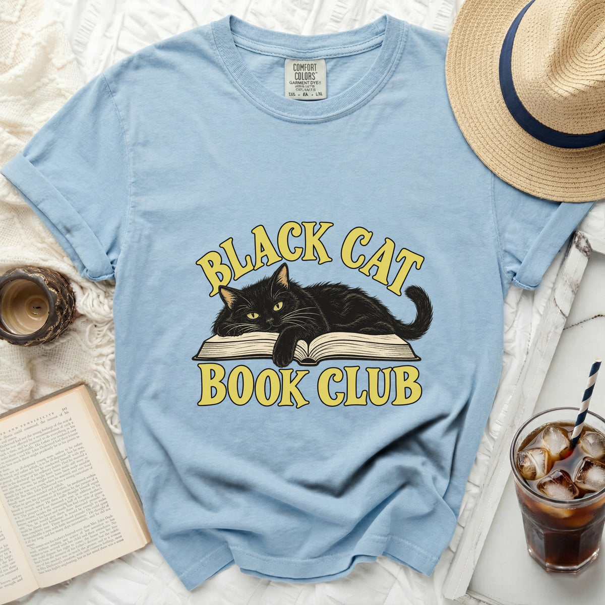Light blue t-shirt with a black cat on an open book graphic reading "BLACK CAT BOOK CLUB".