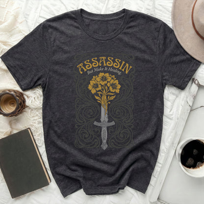 Dark grey t-shirt with sword and flowers design, text "ASSASSIN BUT MAKE IT HEALING."