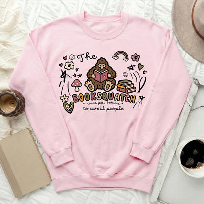 Pink sweatshirt with "The Booksquatch reads past bedtime to avoid people" graphic.