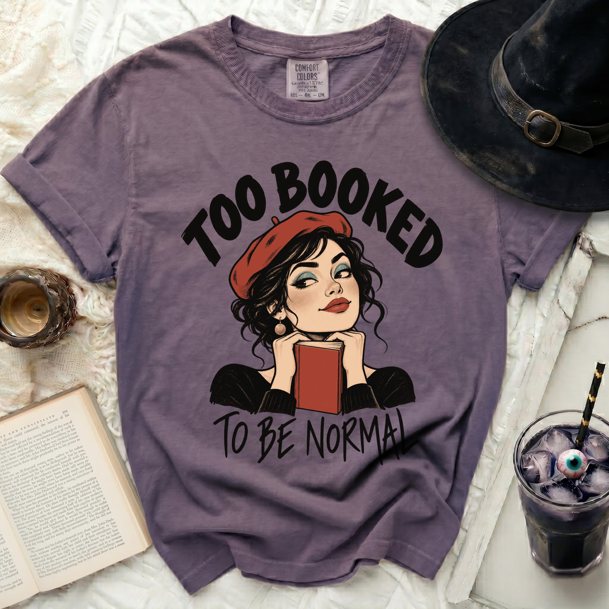 Purple t-shirt with "Too Booked to Be Normal" text and illustration.