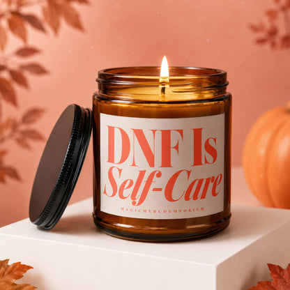Amber candle with lit wick, reads "DNF Is Self-Care" and "MAGICMERCHEMPORIUM".