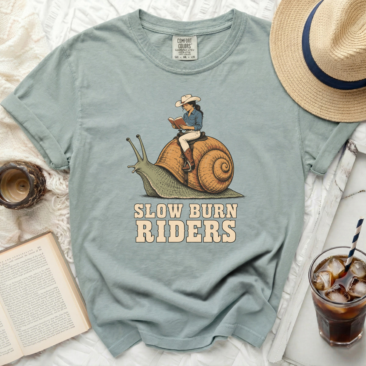 T-shirt with graphic of woman riding snail and text "SLOW BURN RIDERS."
