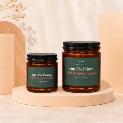 Two amber candles with dark green labels reading "One Fae Prince, Gift Wrapped, Please."