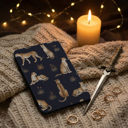 Book cover with cheetah pattern, lit candle, string lights, dagger, and rings on blanket.