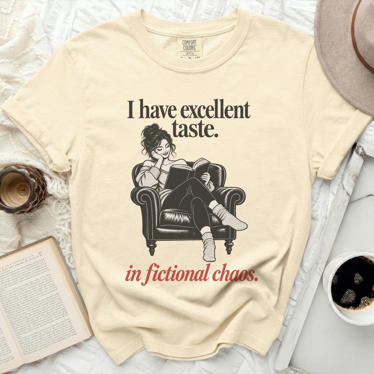 Cream t-shirt with "I have excellent taste. in fictional chaos." text and illustration.