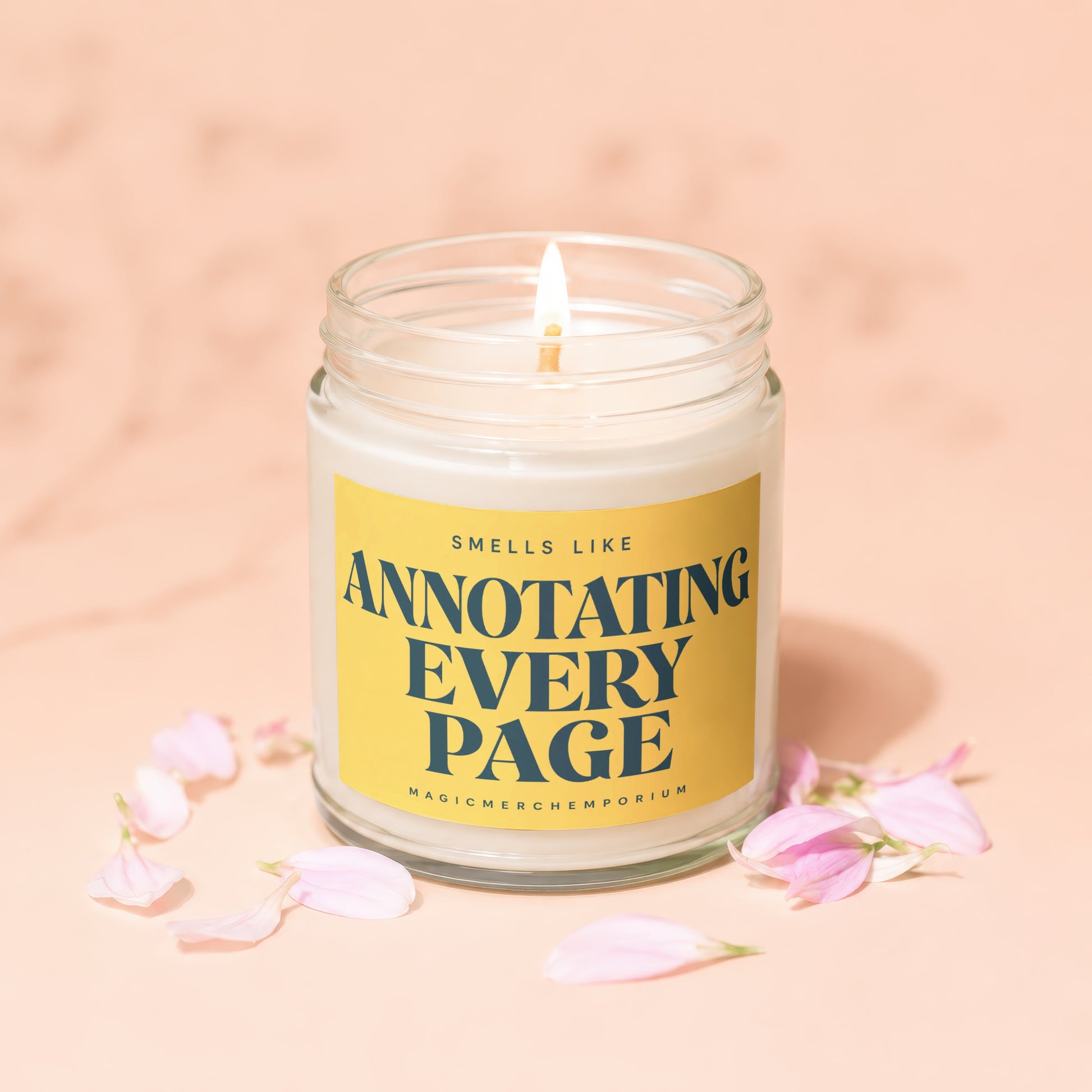 Glass candle with lit wick and yellow label reading "Smells Like Annotating Every Page".