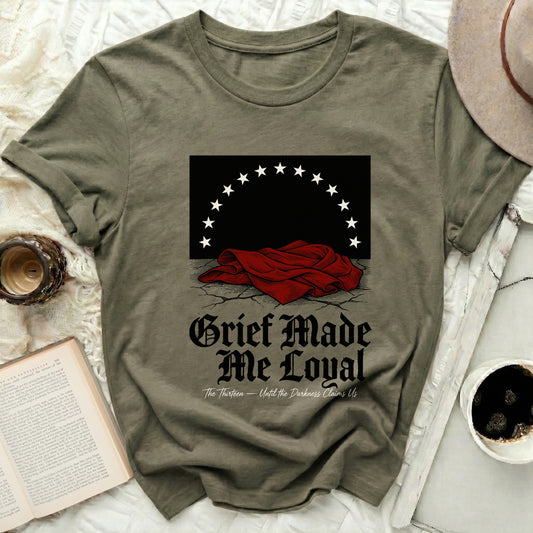 Olive green t-shirt with "Grief Made Me Loyal" text and stars.
