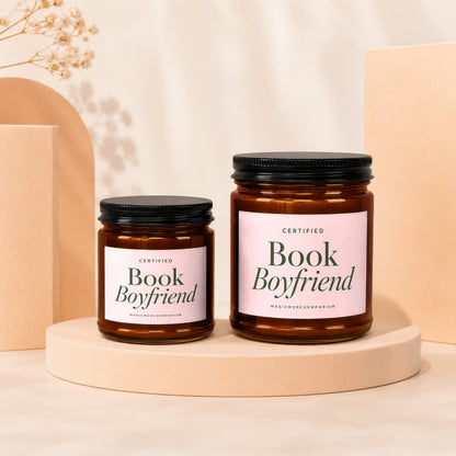 Two amber glass candles with black lids and pink labels reading "Book Boyfriend"