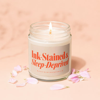 Jar candle with "Ink-Stained & Sleep-Deprived" text, surrounded by pink petals.