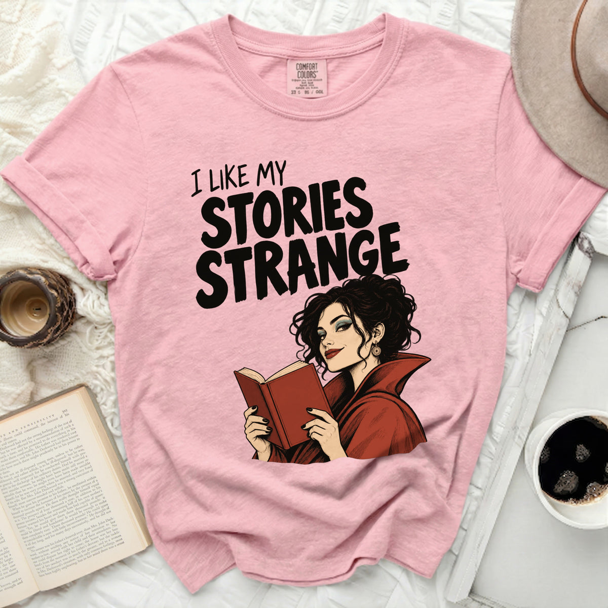 Pink t-shirt with "I like my stories strange" and illustration.