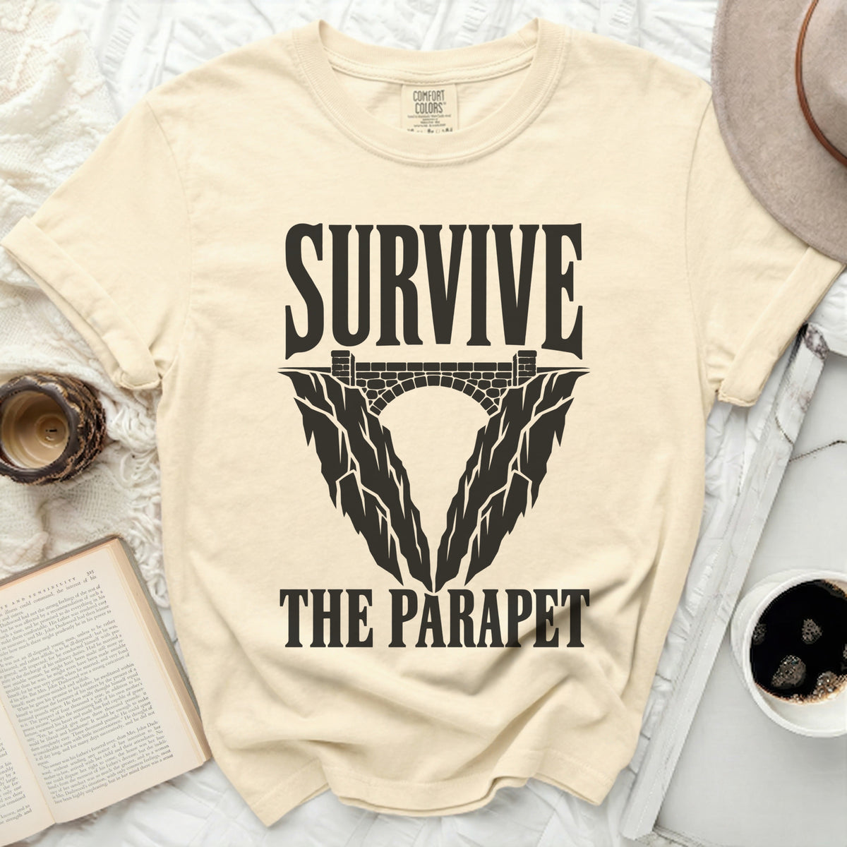 Cream t-shirt with "SURVIVE THE PARAPET" graphic featuring a bridge and cliff design.