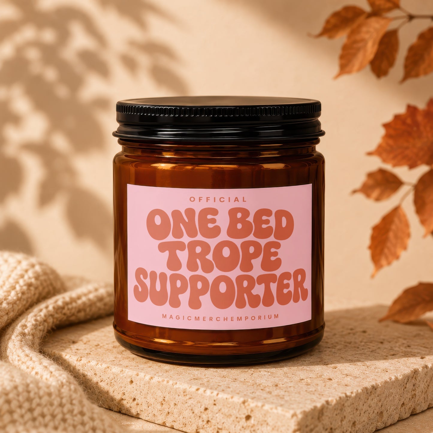 Amber jar candle with pink label reading "OFFICIAL ONE BED TROPE SUPPORTER"