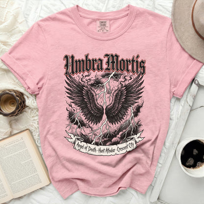 Pink t-shirt with black winged skull graphic and "Umbra Mortis" text.