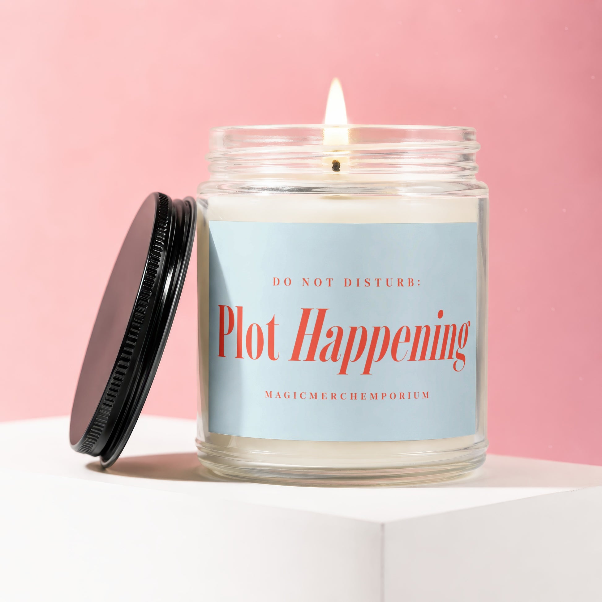 Lit jar candle with a light blue label reading "DO NOT DISTURB: Plot Happening"