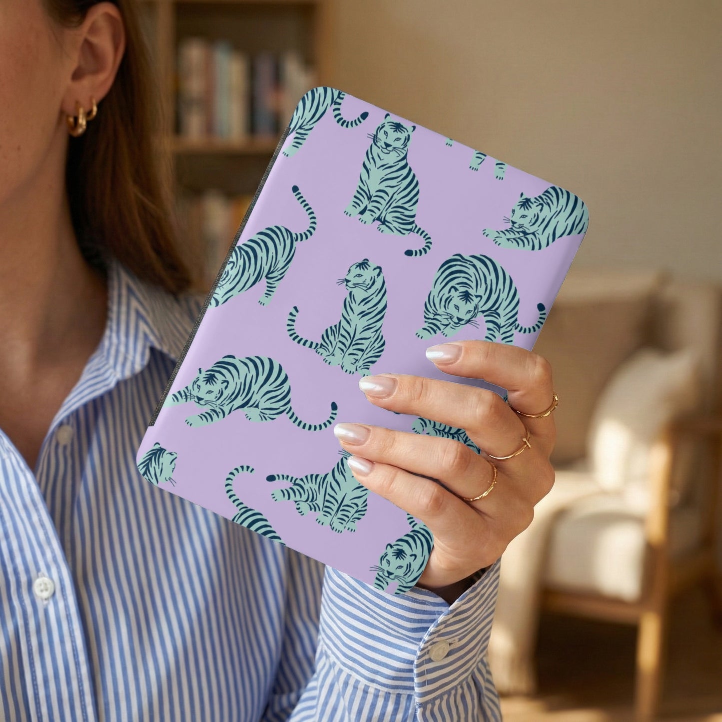 Lavender patterned case with teal tigers, held by a person wearing a blue and white striped shirt.