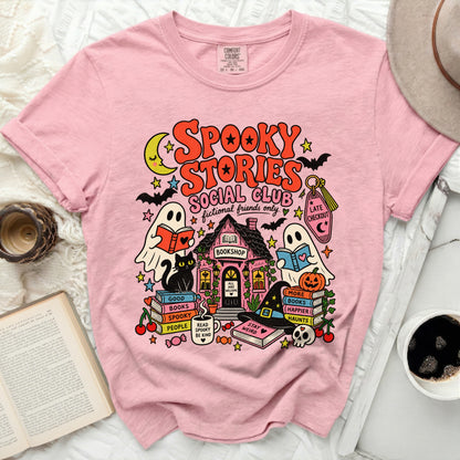 Pink t-shirt with "Spooky Stories Social Club" graphic and Halloween bookshop scene.