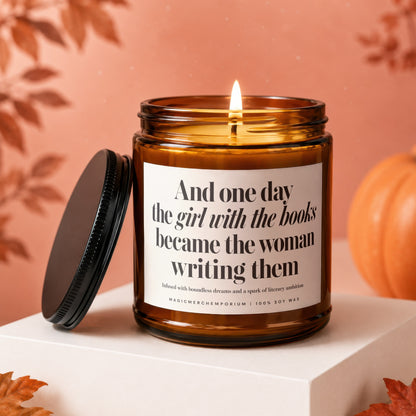 Amber candle with text "The girl with the books became the woman writing them."
