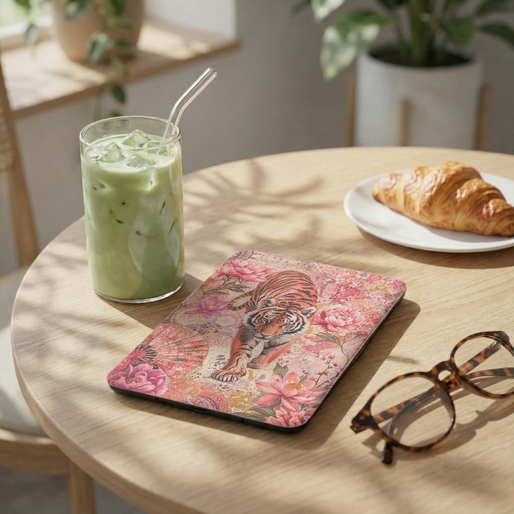 Tablet case with tiger and floral print, next to iced matcha and a croissant.