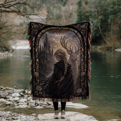 A person stands in front of a large tapestry depicting a castle and a deer, with a river and trees in the background.