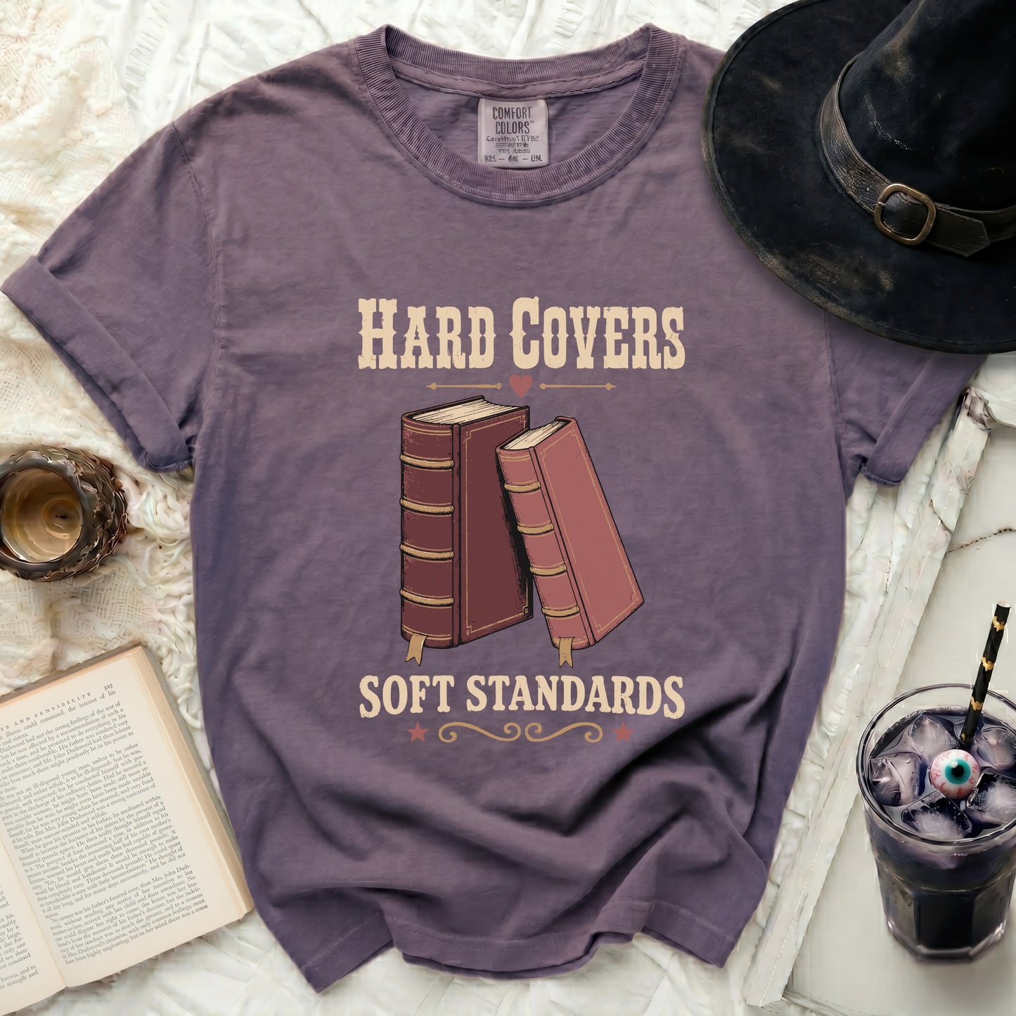 Purple t-shirt with "HARD COVERS SOFT STANDARDS" and two books.