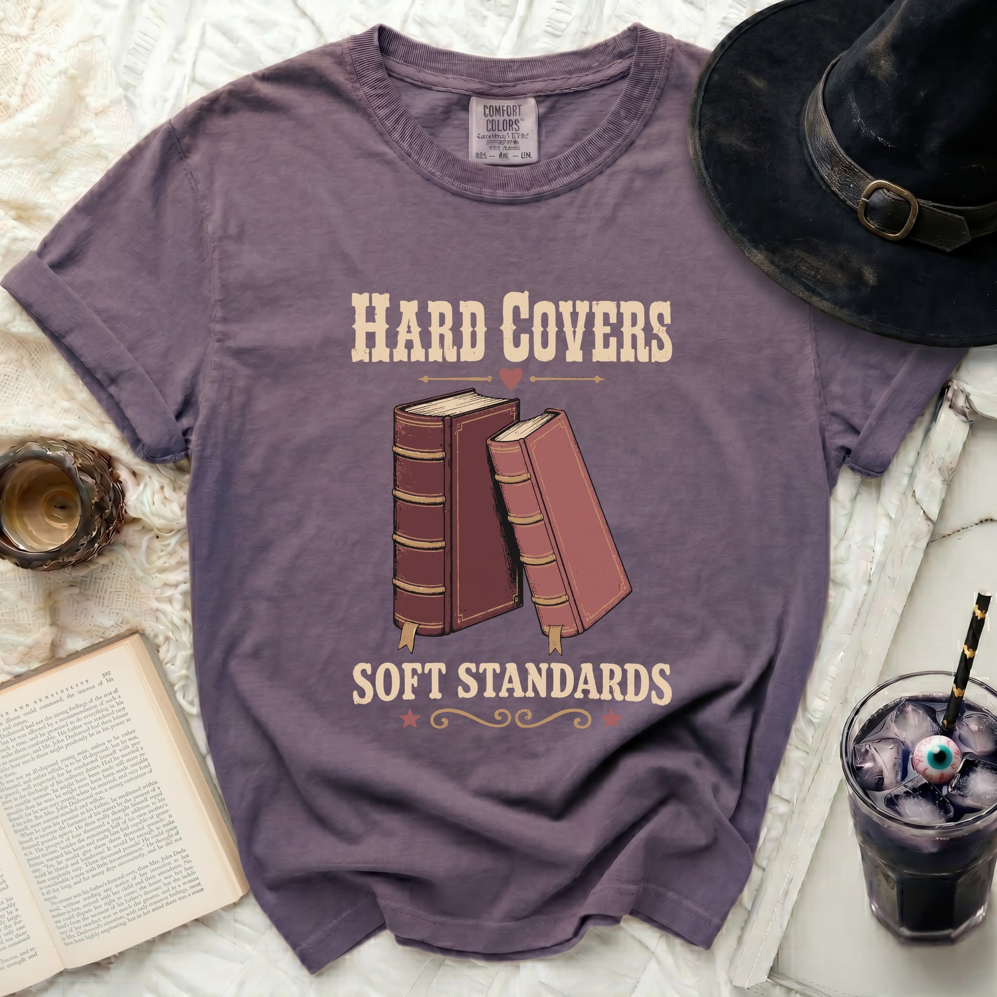 Purple t-shirt with "HARD COVERS SOFT STANDARDS" and two books.
