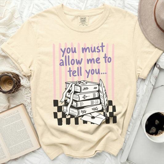 Cream comfort colors t-shirt with purple text and book illustration.