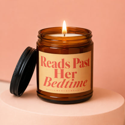 Amber jar candle with lit flame and lid off, labeled "Reads Past Her Bedtime".