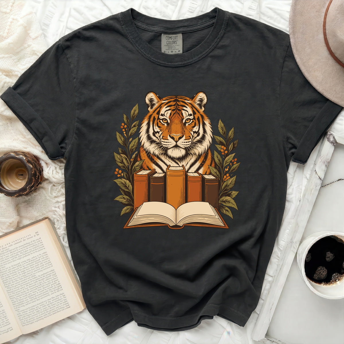 T-shirt featuring a tiger surrounded by books and foliage, "Comfort Colors" label visible.