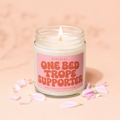Candle with pink label reading "OFFICIAL ONE BED TROPE SUPPORTER".