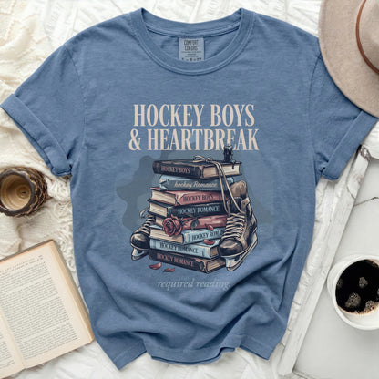 Blue t-shirt with stack of books and hockey skates, "Hockey Boys & Heartbreak" text.