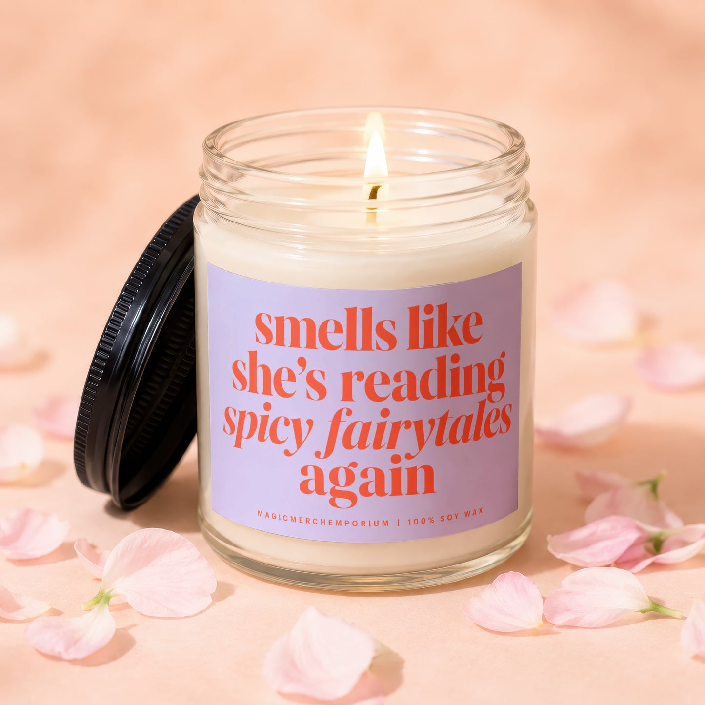 Candle with lit wick and purple label reading "smells like she's reading spicy fairytales again".