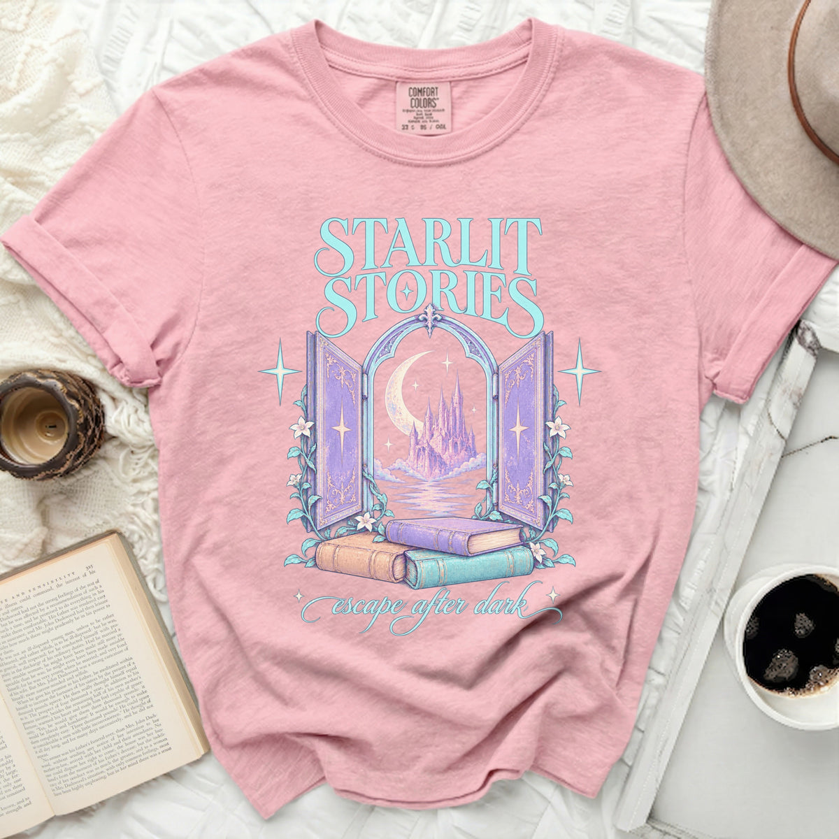 Pink t-shirt with "Starlit Stories" text and castle scene graphic.