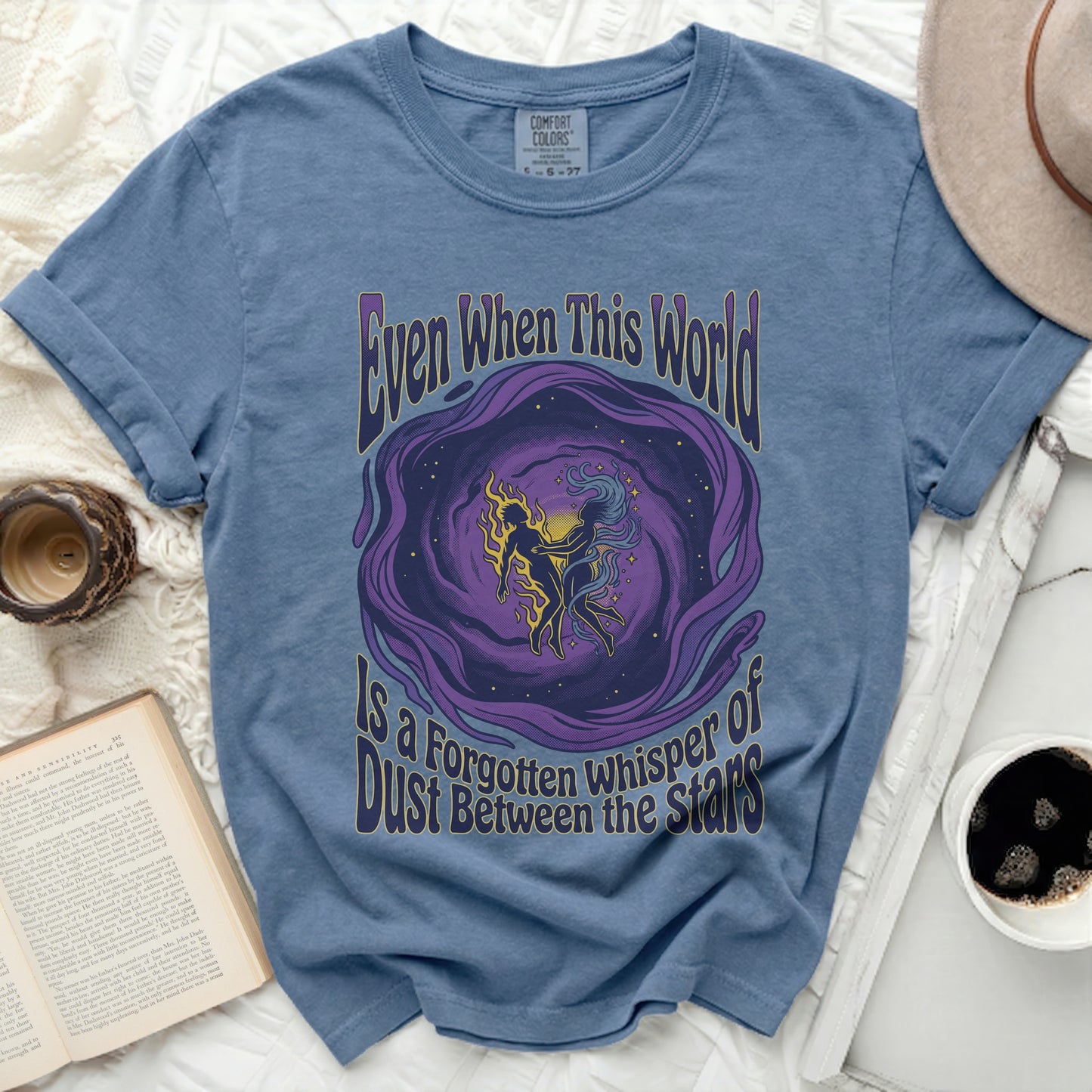 Blue t-shirt with purple cosmic design and text "Even When This World Is A Forgotten Whisper Of Dust Between the Stars".
