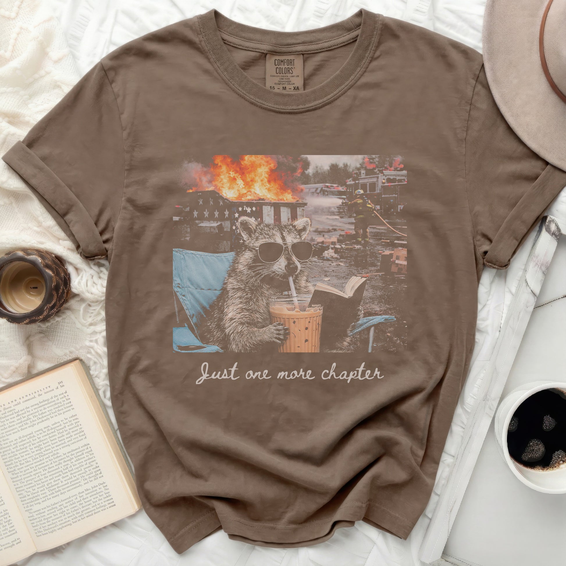 T-shirt with raccoon in sunglasses reading with burning house behind.