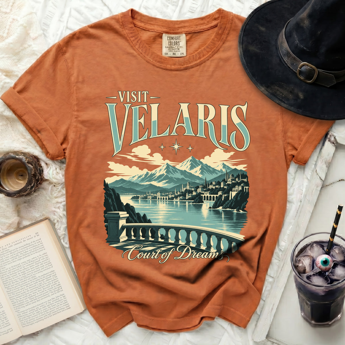 Orange t-shirt with "Visit Velaris Court of Dream" text and cityscape design.