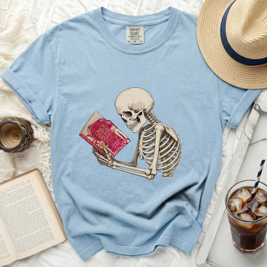 Skeleton reading a book titled "Once Upon a Broken Heart" on a light blue shirt.